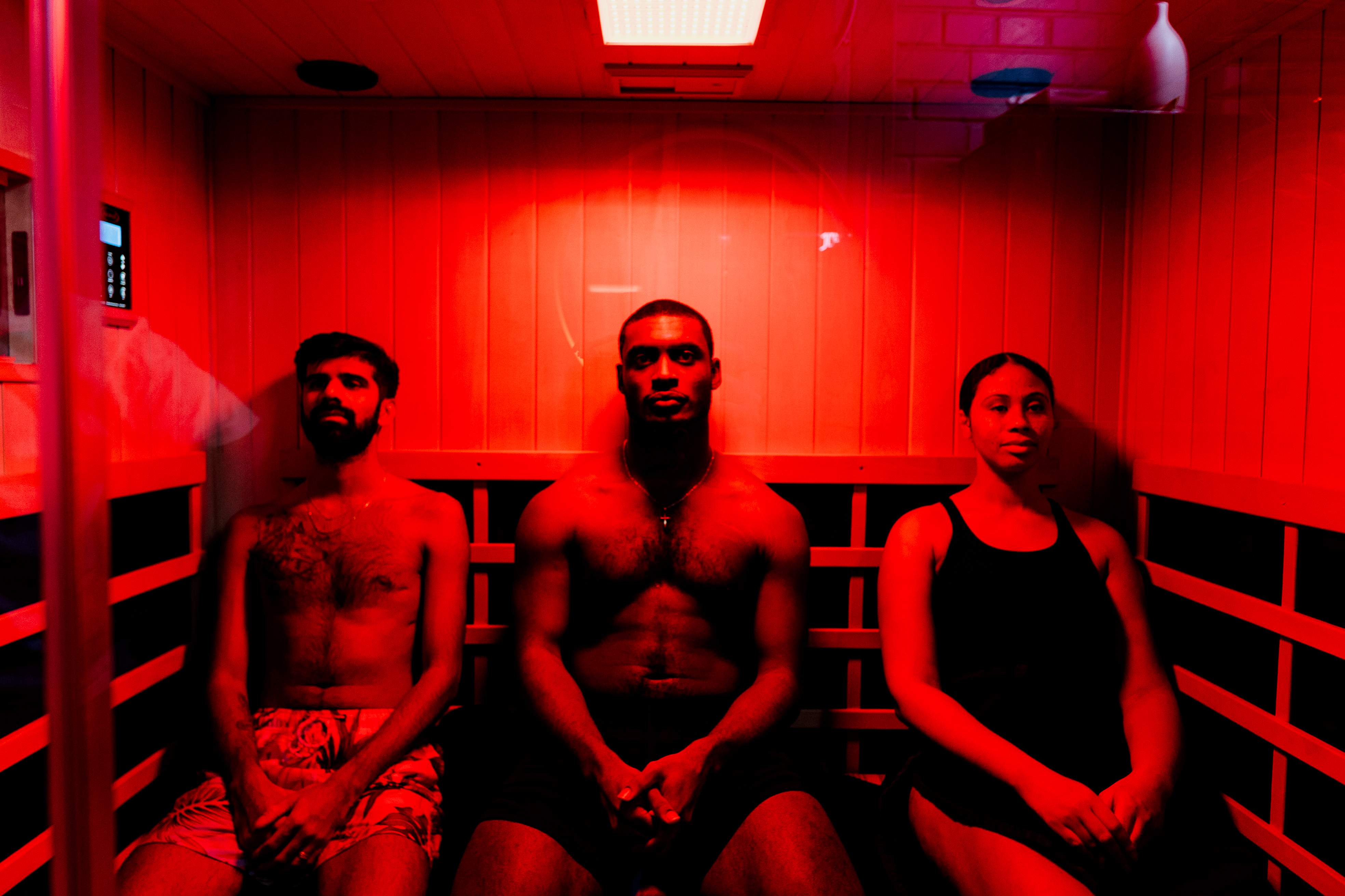 Three people enjoying a session in dimly lit traditional sauna.