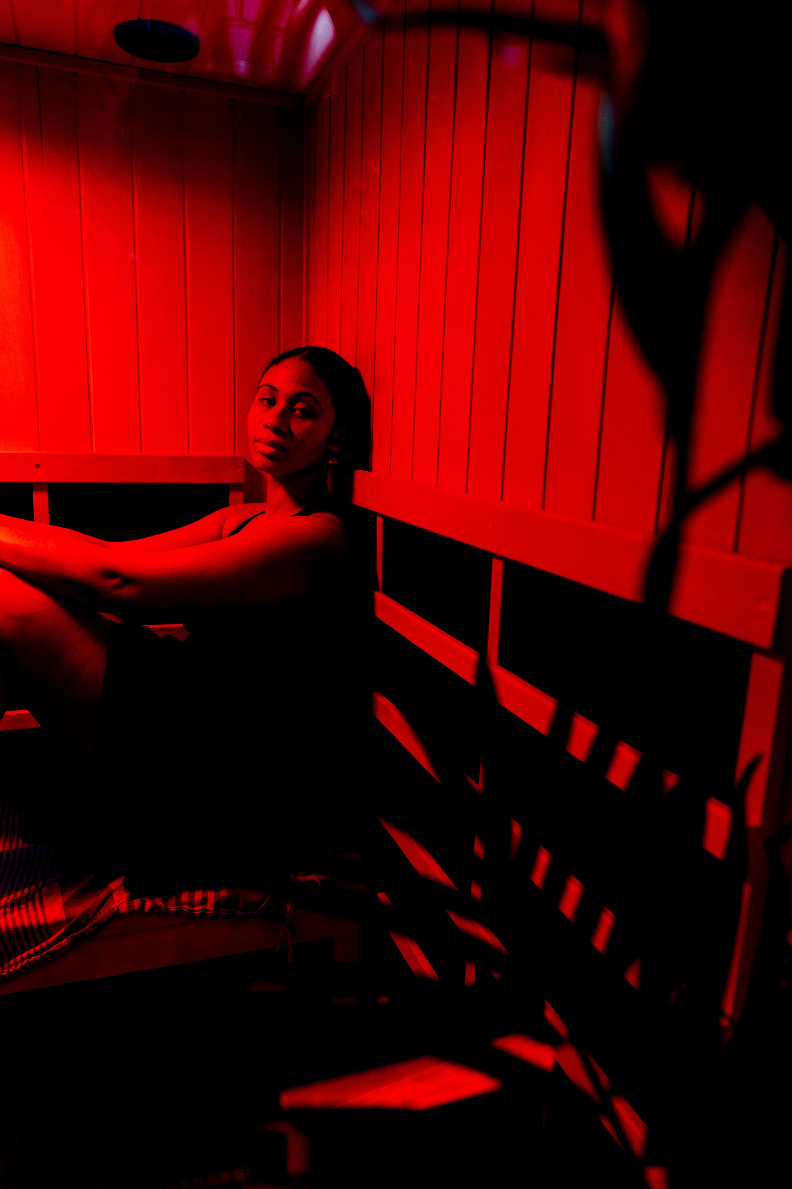A person relaxing on a cedar bench inside a sauna for heat therapy and wellness.