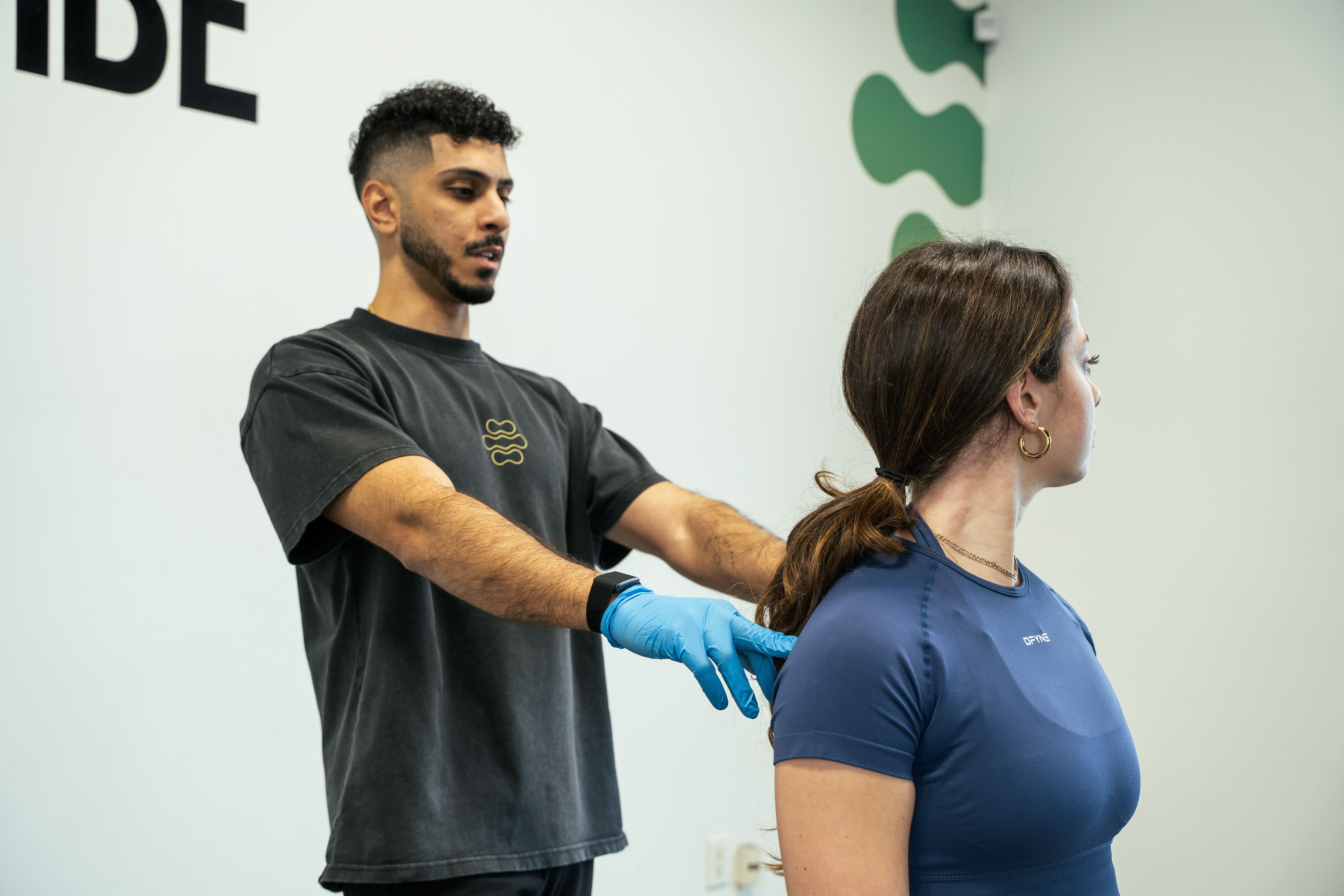 Physiotherapist measuring shoulder height to check for imbalances.