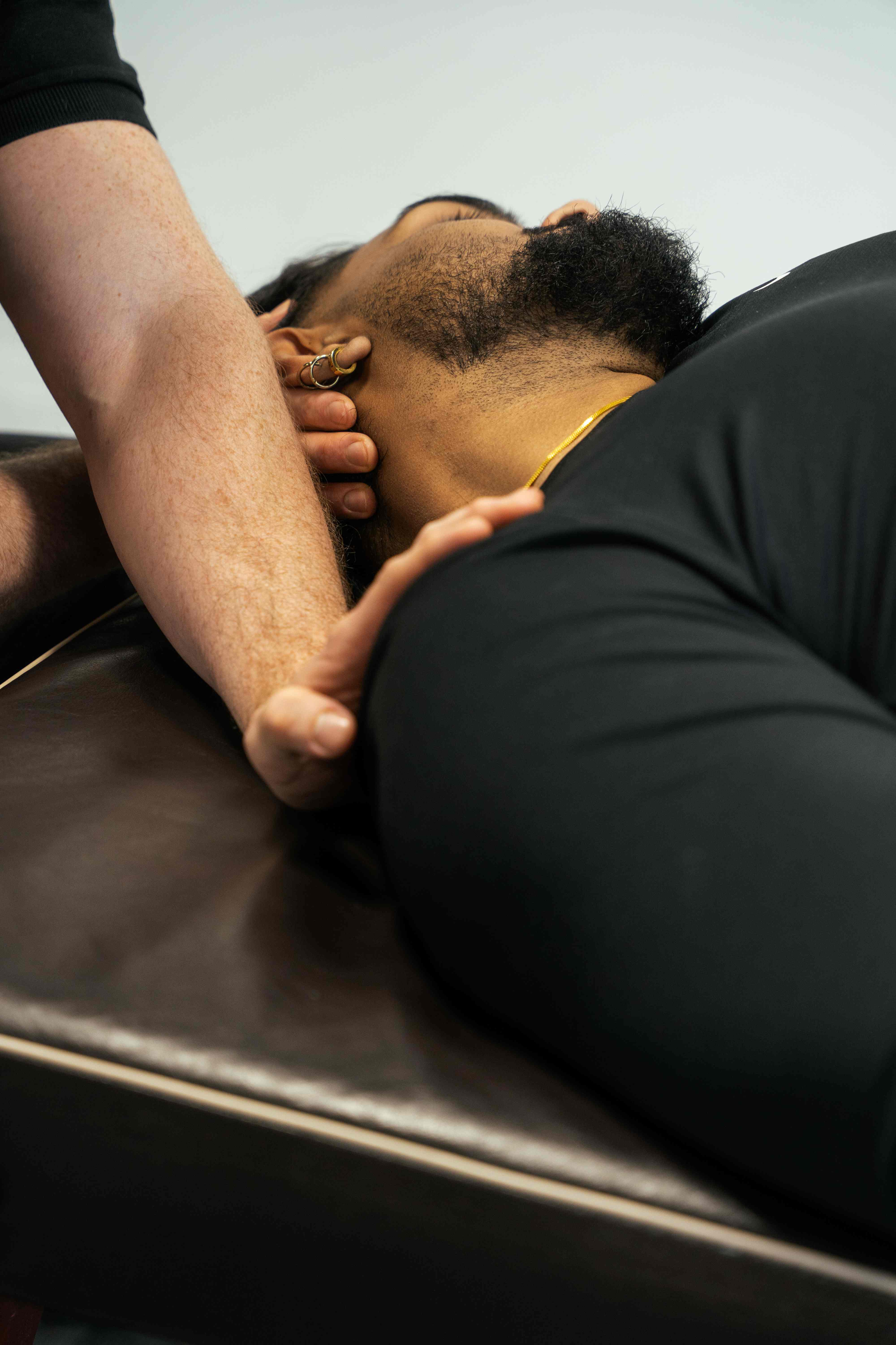 Physiotherapist using trigger point therapy on a patient's neck to relieve tension headaches.