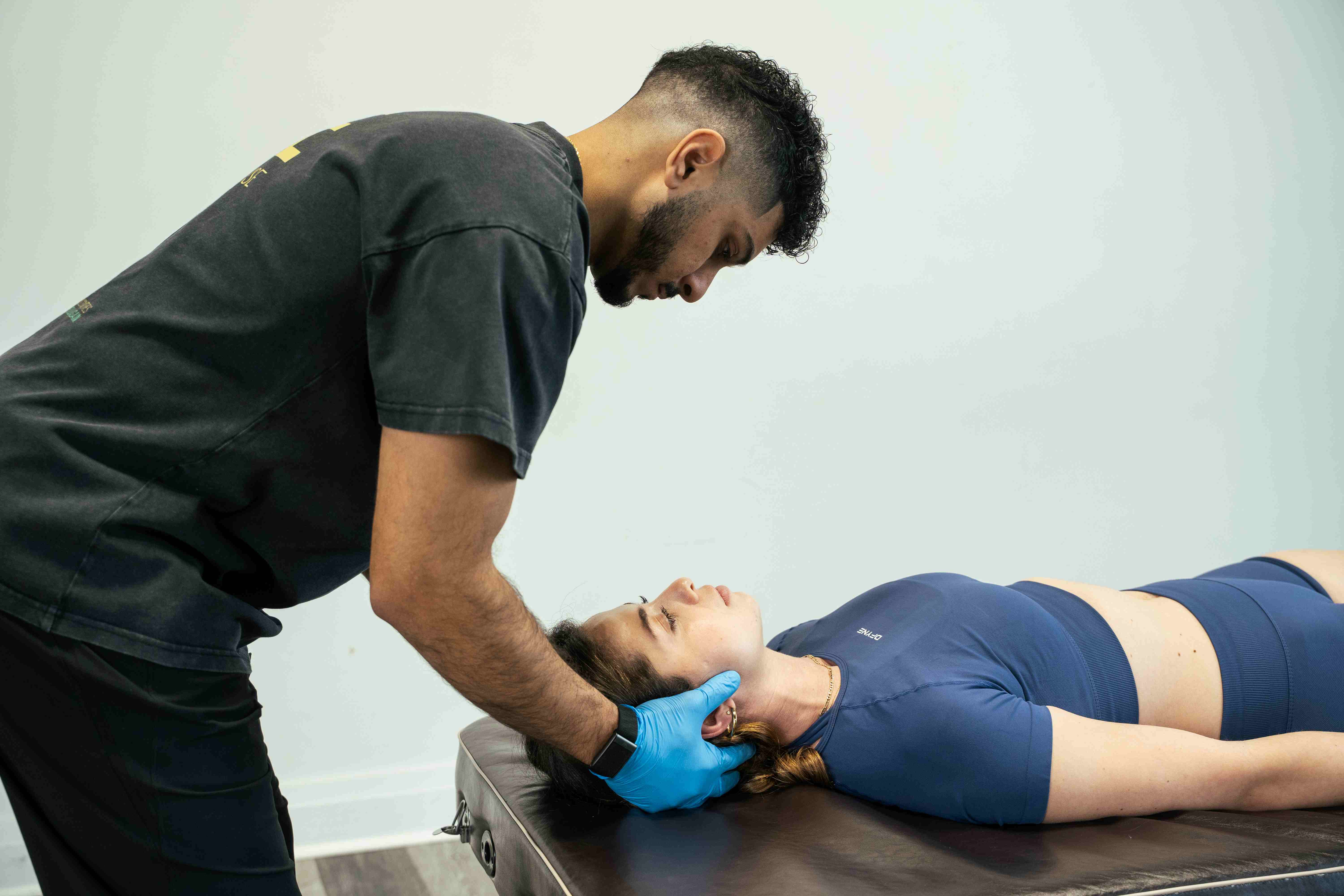 Physiotherapist evaluating a patient's forward head posture and neck curvature.