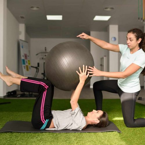 Physical therapist assisting young caucasian woman with exercise